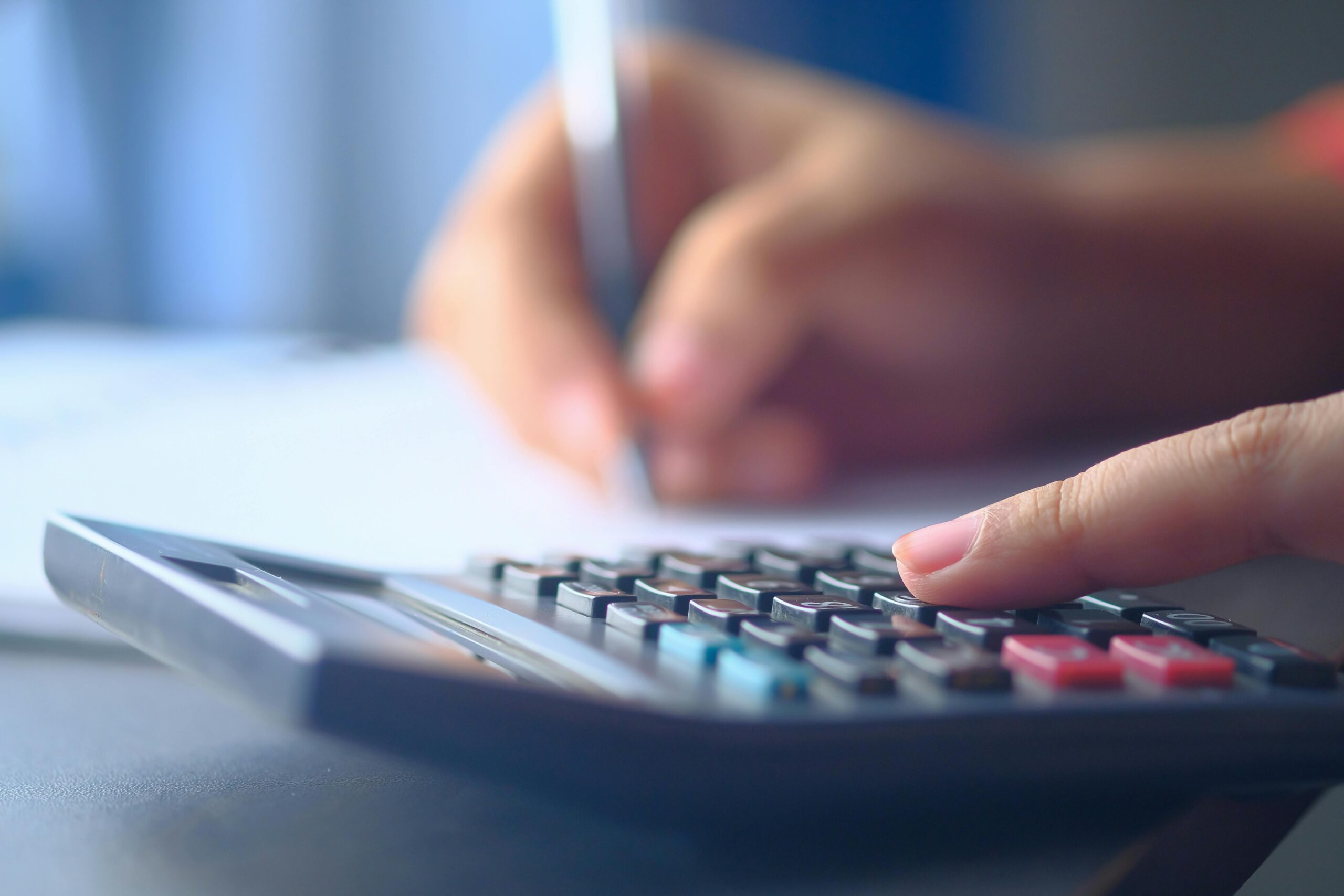 pexels-photo-11350076-11350076 A close-up image of hands working on a calculator and writing, representing budgeting and financial planning.