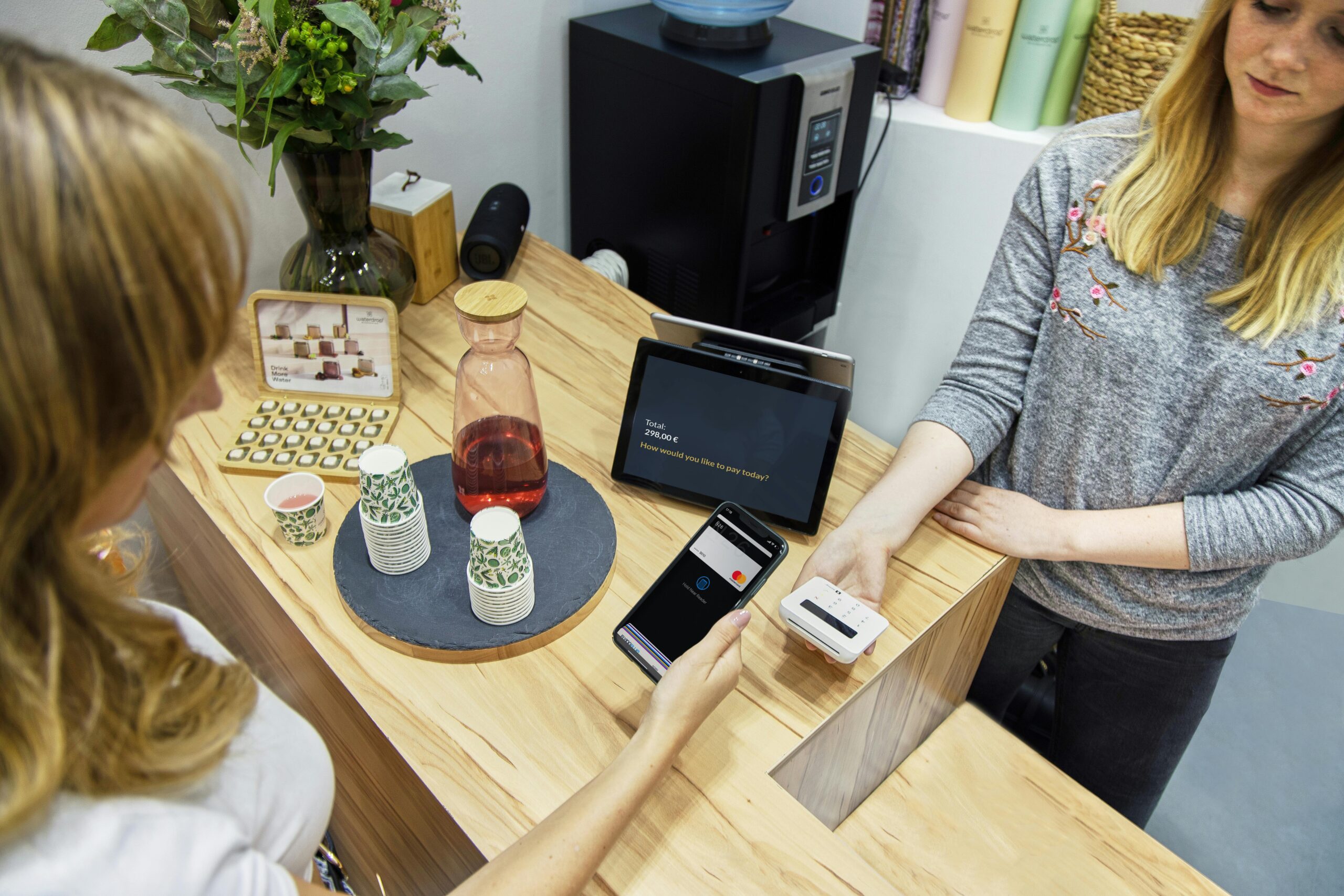 A woman makes a contactless payment at a stylish Berlin café, emphasizing technology and modern retail.
